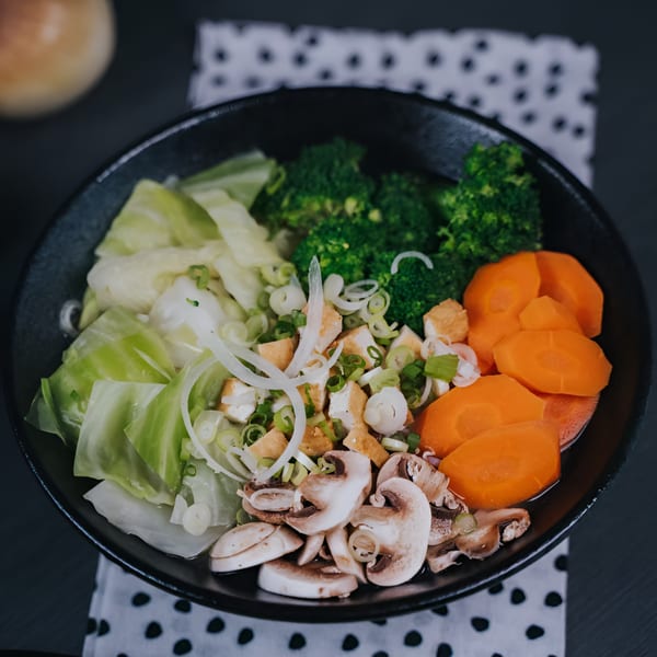 A Vietnamese fusion bowl with broccoli, cabbage, carrots, mushrooms, tofu, and green onions.
